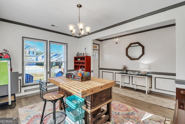 dining area featuring hardwood / wood-style floors, crown molding, and an inviting chandelier