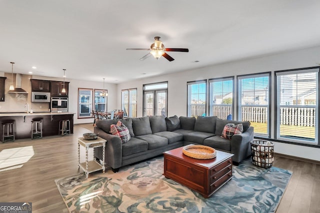 living room featuring ceiling fan, plenty of natural light, and light hardwood / wood-style floors