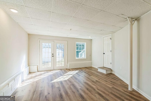 unfurnished room with a paneled ceiling, french doors, and wood-type flooring