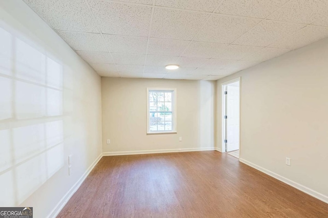 unfurnished room featuring hardwood / wood-style floors and a paneled ceiling