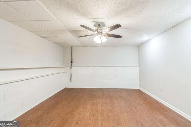 empty room with a paneled ceiling, ceiling fan, and wood-type flooring