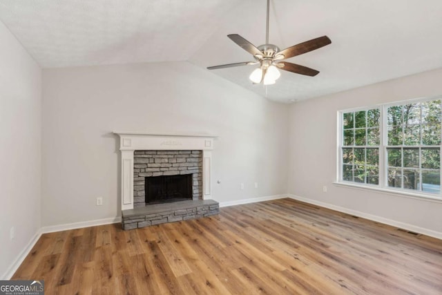 unfurnished living room featuring a stone fireplace, ceiling fan, light hardwood / wood-style flooring, and vaulted ceiling