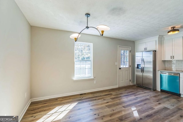 kitchen featuring hardwood / wood-style floors, decorative backsplash, white cabinetry, and stainless steel appliances