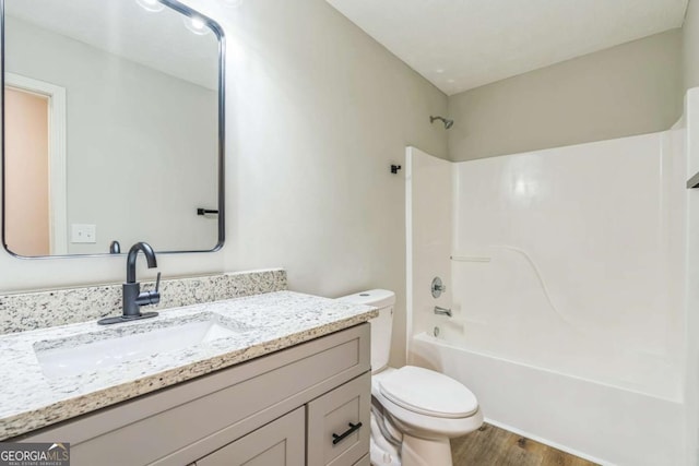 full bathroom featuring shower / washtub combination, vanity, wood-type flooring, and toilet