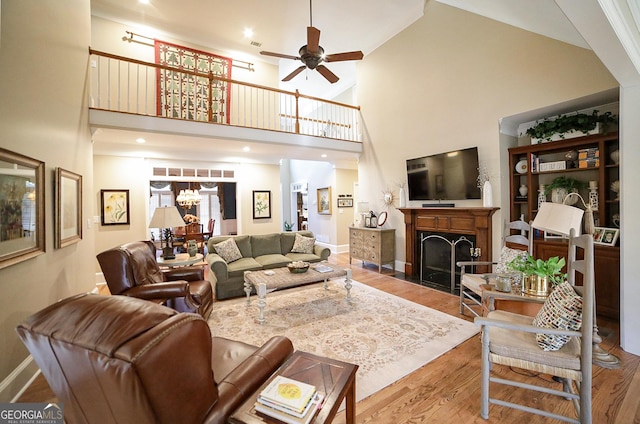 living room featuring hardwood / wood-style flooring, ceiling fan with notable chandelier, and high vaulted ceiling