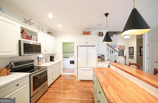 kitchen with butcher block counters, white cabinetry, hanging light fixtures, washer and dryer, and appliances with stainless steel finishes