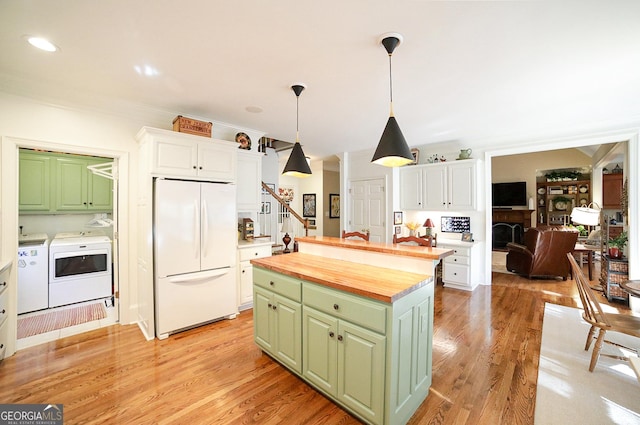 kitchen featuring a kitchen island, washing machine and dryer, white fridge, light hardwood / wood-style floors, and white cabinetry