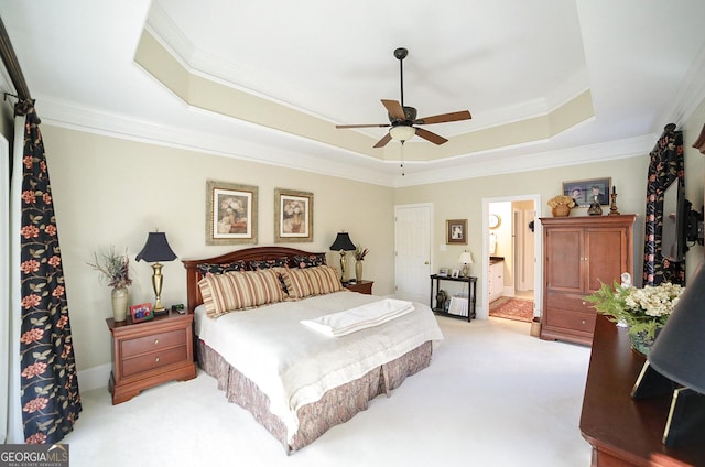 bedroom with light carpet, ensuite bathroom, a tray ceiling, ceiling fan, and crown molding