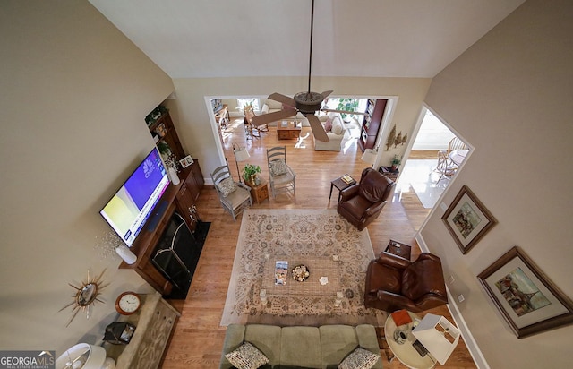 living room with ceiling fan, light hardwood / wood-style floors, and lofted ceiling