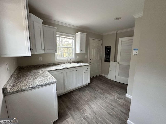 kitchen with dark wood-type flooring, white cabinets, crown molding, sink, and stone countertops