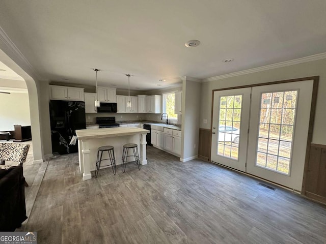 kitchen with crown molding, white cabinetry, black appliances, and light wood-type flooring