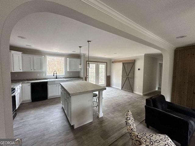 kitchen featuring white cabinetry, hanging light fixtures, black dishwasher, hardwood / wood-style floors, and a kitchen island