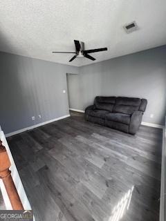 unfurnished living room with dark hardwood / wood-style floors, ceiling fan, and a textured ceiling