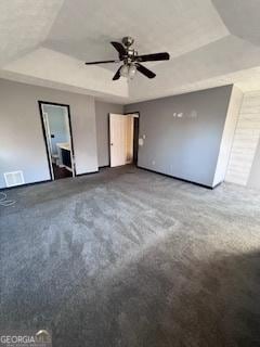 unfurnished bedroom featuring carpet, ceiling fan, a raised ceiling, and ensuite bath