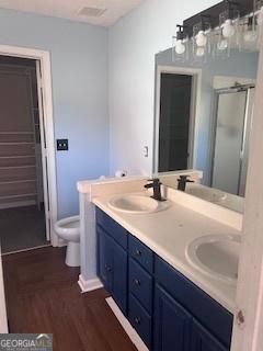 bathroom featuring hardwood / wood-style floors, vanity, toilet, and an enclosed shower