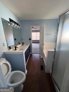 bathroom with a washtub, wood-type flooring, vanity, and toilet