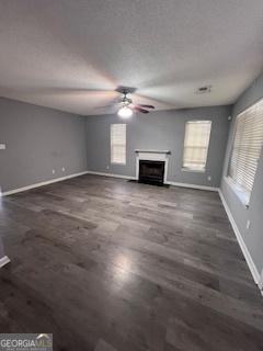 unfurnished living room featuring ceiling fan and dark wood-type flooring