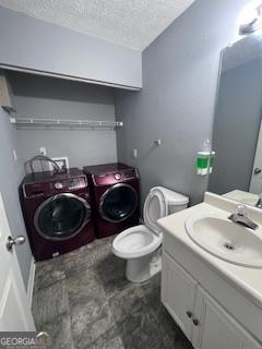 bathroom with washer and clothes dryer, vanity, toilet, and a textured ceiling