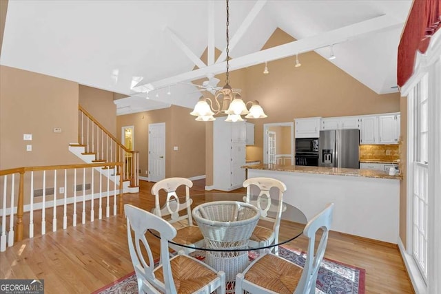 dining room with a chandelier, light hardwood / wood-style floors, high vaulted ceiling, and plenty of natural light