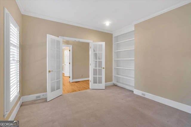 spare room featuring french doors, carpet, built in features, and ornamental molding