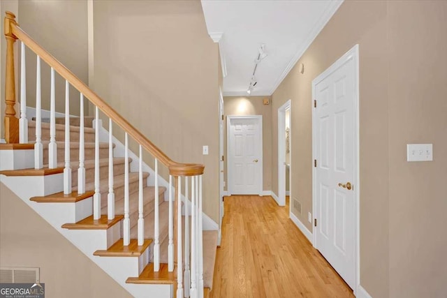 foyer featuring light hardwood / wood-style floors, crown molding, and track lighting