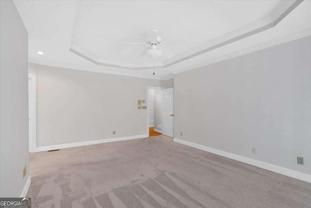 unfurnished room featuring a tray ceiling, ceiling fan, and light colored carpet