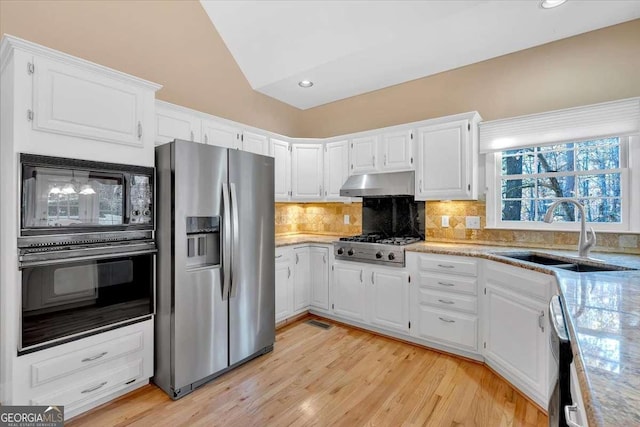 kitchen with black appliances, sink, tasteful backsplash, light hardwood / wood-style floors, and white cabinetry