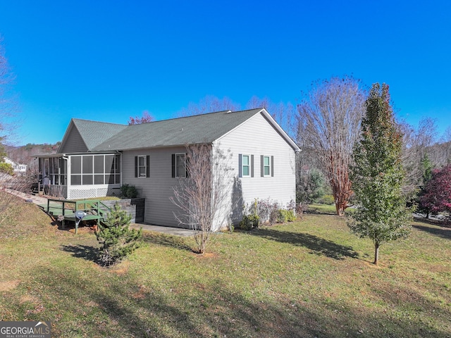 rear view of house featuring a sunroom and a lawn