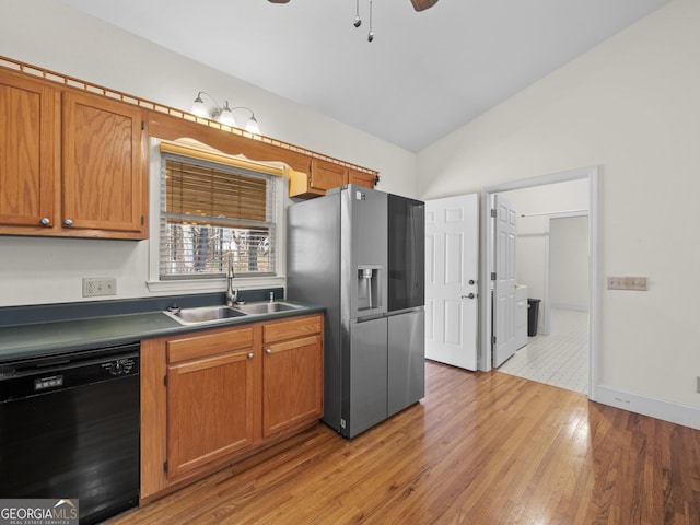 kitchen featuring sink, vaulted ceiling, black dishwasher, light hardwood / wood-style floors, and stainless steel fridge with ice dispenser