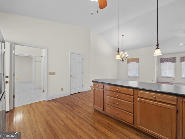 kitchen with ceiling fan with notable chandelier, light hardwood / wood-style floors, high vaulted ceiling, and hanging light fixtures