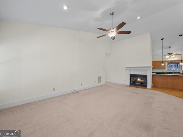 unfurnished living room with ceiling fan, high vaulted ceiling, and light colored carpet