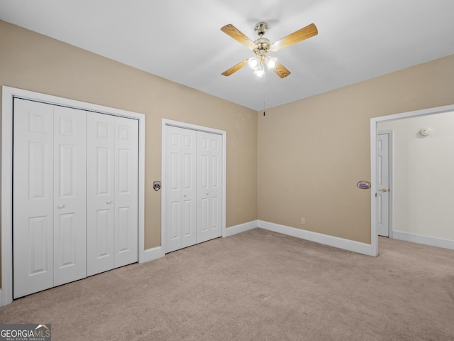 unfurnished bedroom featuring light carpet, two closets, and ceiling fan