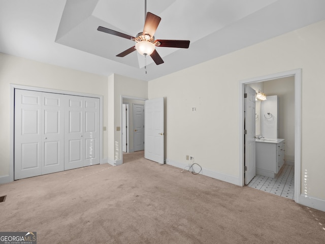 unfurnished bedroom with light colored carpet, ensuite bath, and ceiling fan