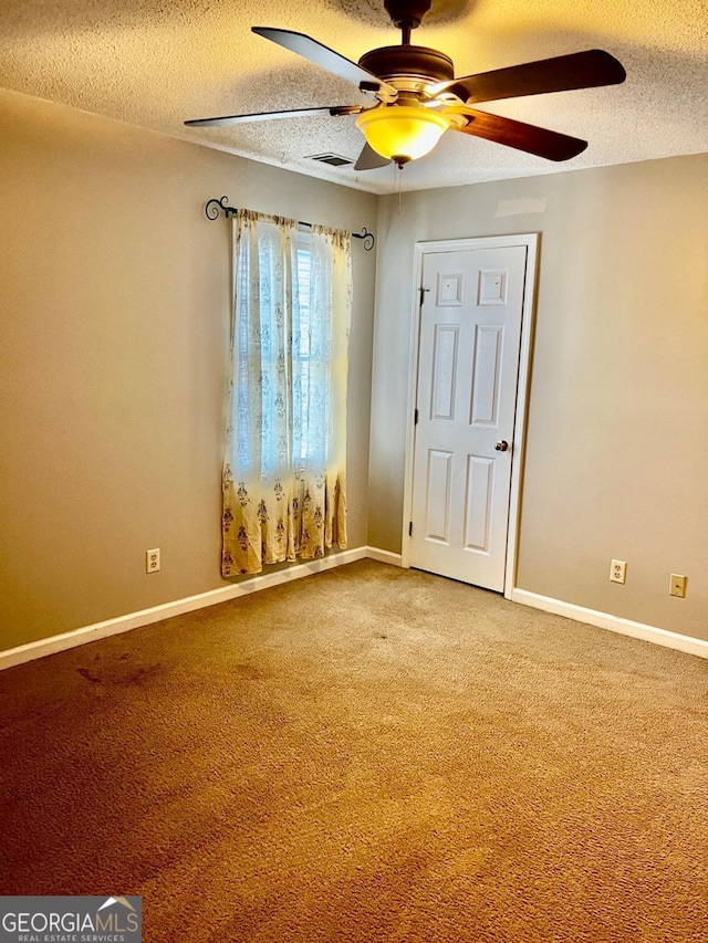 spare room with a textured ceiling, carpet floors, and ceiling fan