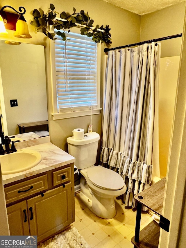 bathroom featuring vanity, a textured ceiling, and toilet