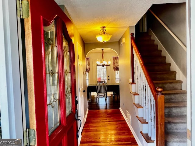 entryway featuring a textured ceiling, a chandelier, and dark hardwood / wood-style floors