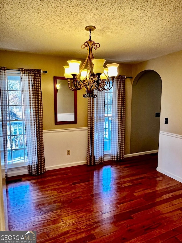 unfurnished room with a notable chandelier, dark hardwood / wood-style floors, and a textured ceiling