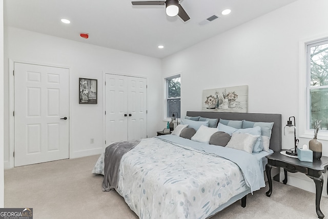 bedroom featuring ceiling fan, light colored carpet, and multiple windows