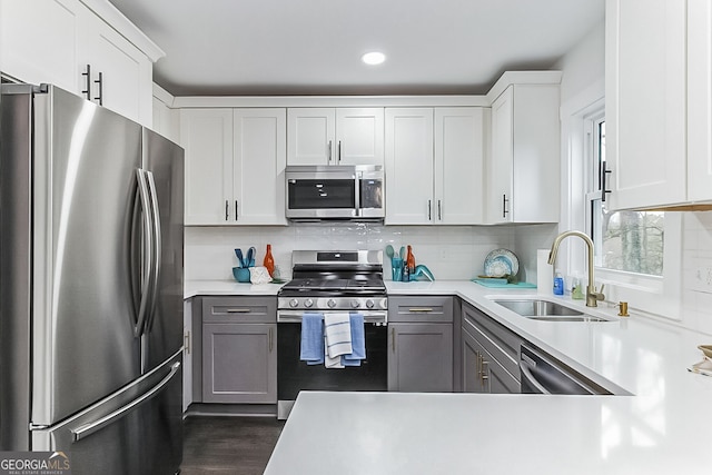 kitchen with backsplash, sink, gray cabinets, white cabinetry, and stainless steel appliances