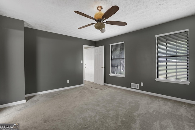 spare room with carpet floors, a wealth of natural light, and ceiling fan