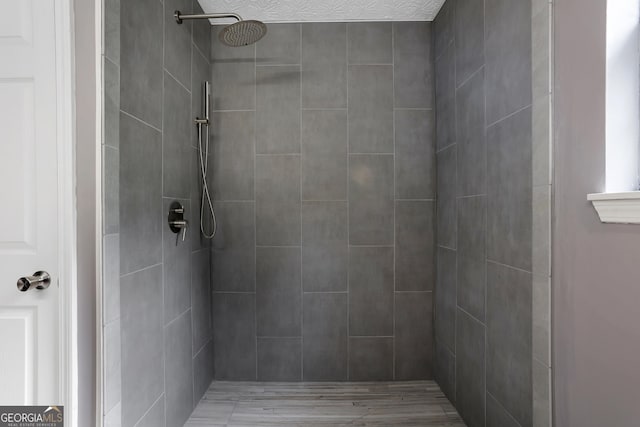 bathroom with hardwood / wood-style flooring and a tile shower