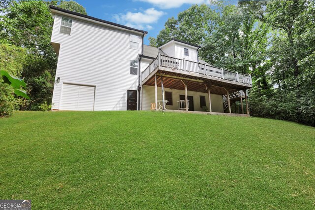 back of house featuring a garage, a lawn, and a wooden deck