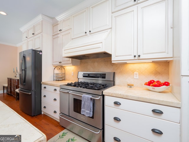 kitchen featuring stainless steel appliances, backsplash, light hardwood / wood-style floors, custom range hood, and ornamental molding