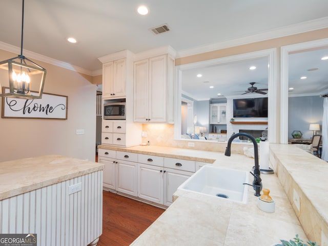 kitchen featuring sink, dark hardwood / wood-style floors, pendant lighting, ceiling fan with notable chandelier, and ornamental molding