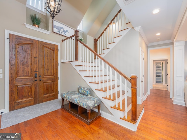 foyer featuring hardwood / wood-style flooring, a notable chandelier, and ornamental molding