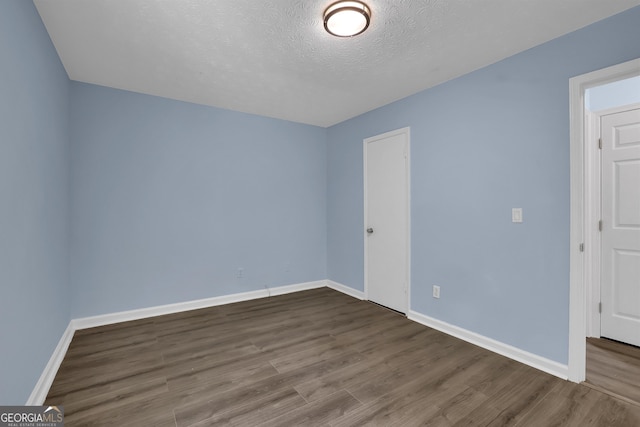 unfurnished room with wood-type flooring and a textured ceiling