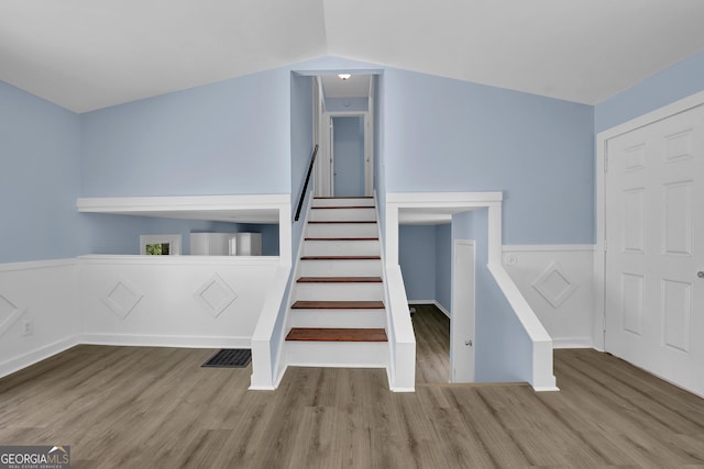 stairs featuring vaulted ceiling and hardwood / wood-style flooring