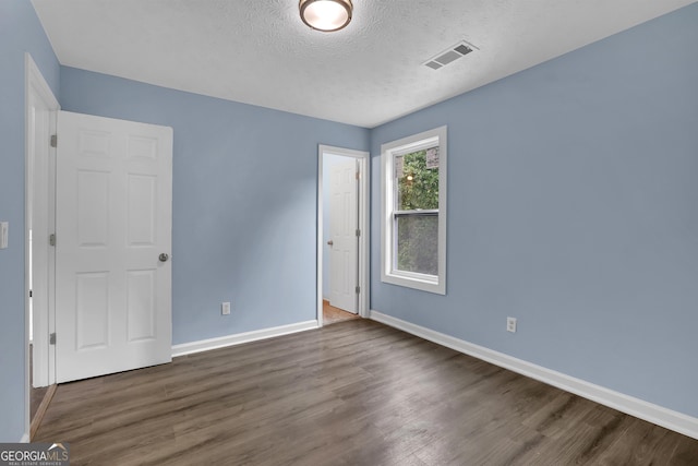 empty room with a textured ceiling and dark hardwood / wood-style floors