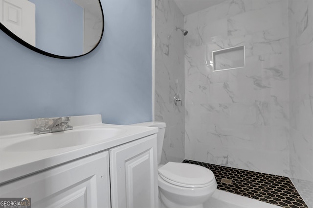 bathroom featuring tiled shower, vanity, and toilet