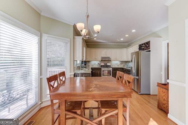 dining room with crown molding, light hardwood / wood-style flooring, and a chandelier